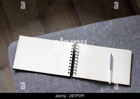 Un carnet blanc ouvert avec ressorts se trouve sur un canapé gris. Espace pour le texte Banque D'Images