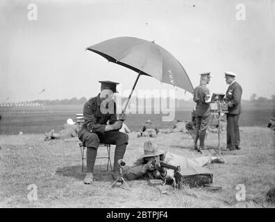 Ouverture de la réunion du fusil Bisley . La 71e réunion du prix de l'association nationale de carabines s'est ouverte au camp de Bisley , Surrey . Photos , Lieut Stephen Johnson , de Calgarry (Alberta) , prenant un cliché de pratique , sous un parapluie , tenu par un Tommy britannique . 9 juillet 1934 Banque D'Images