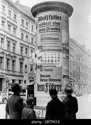 Fièvre électorale en Allemagne . La lecture d'une affiche électorale à Berlin , qui comme le reste de l'Allemagne , est maintenant au cœur de la campagne électorale nazie . L'affiche est dirigée ' Adolf Hitler conquiert une nouvelle province ' et continue à se référer à la Sear et à d'autres réalisations nazies . 13 mars 1936 Banque D'Images