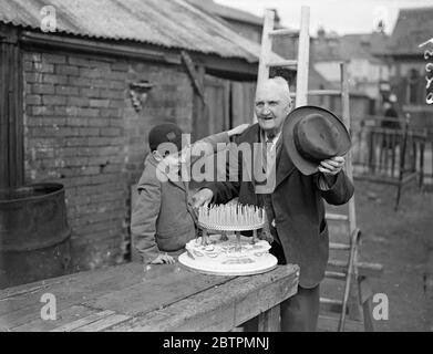 106 ans . Jimmy Miles , célèbre centenaire de Southampton , célèbre son anniversaire de 106 . Photos , Jimmy Miles coupant son gâteau d'anniversaire de 106 regardé par son petit-fils plus jeune. 17 mars 1937 Banque D'Images