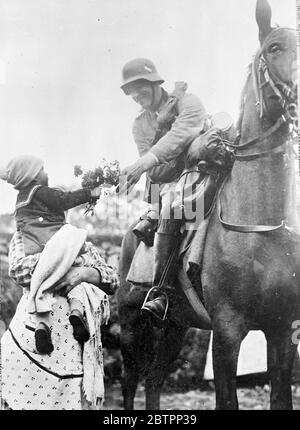 Les Allemands ont marché en Tchécoslovaquie, les premières photos originales à rejoindre Londres. Ce sont les premières images originales à atteindre Londres de l'occupation par les armées d'Hitler des régions des Sudètes en Tchécoslovaquie. Des avions spécialement affrétés et une voiture de plus de 200 miles ont été impliqués dans la transmission de ces photos en Angleterre. Spectacles de photos, un soldat allemand, en casque d'acier, reçoit une posy de fleurs d'un enfant des Sudètes dans les bras de sa mère à Ludwigsthal à la frontière. 2 octobre 1938 Banque D'Images