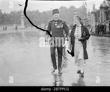 À l'investiture de Buckingham Palace. Une investiture a été organisée par le Roi au Palais de Buckingham, le premier à y avoir lieu pendant plusieurs années. La participation a été principalement constituée d'admissions et de promotions dans les classes supérieures des ordres de Chivalry, faites dans les honneurs d'anniversaire. Expositions de photos, le major Wallace Bey et sa femme arrivent à Buckingham Palce. 5 juillet 1938 Banque D'Images