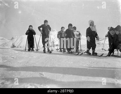 Premiers pas de ski. Un groupe d'enfants qui se latent de la tenue incorrecte et avec des skis bien faits, ont leur première leçon dans l'art complexe du ski à St Moritz, Suisse. 30 décembre 1937 Banque D'Images