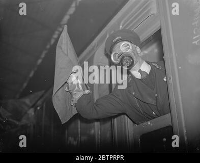 « protégé » contre le gaz. Formation anti Air RAID à Euston. Et l'unité d'enseignement mobile IMS Air RAID précaution était en vue à la gare Euston, à Londres. L'unité est constituée de deux véhicules, l'un d'un entraîneur de conférence et l'autre d'un entraîneur de décontamination. Il a été fourni par le chemin de fer IMS dans le cadre d'un programme de formation de leur personnel aux précautions en matière de RAID aérien. L'unité mobile va bientôt entreprendre une visite du système IMS en Angleterre, en Écosse et au pays de Galles. Ils ont l'intention de former près de 23,000 de leurs 230,000 travailleurs à des travaux de RAID aérien. Photos montre, un garde dans un masque à gaz marquage d'un train Banque D'Images