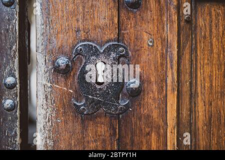 Trou de serrure vintage dans la porte rustique du château médiéval. Ancienne porte en bois avec ferrure en fer. Élément clé décoratif en acier de style rétro fait main. Banque D'Images