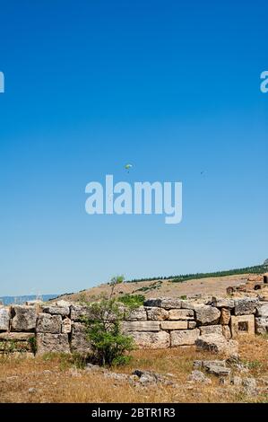 Parapentes survolant les vestiges de l'ancienne ville de Hiérapolis en Turquie. Banque D'Images