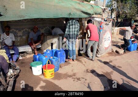 Les citoyens remplissent leurs bidons d'eau du robinet public alors qu'ils sont confrontés à une pénurie d'eau potable dans leur région par temps chaud en été, situé dans la région de Korangi à Karachi le mercredi 27 mai 2020. Banque D'Images