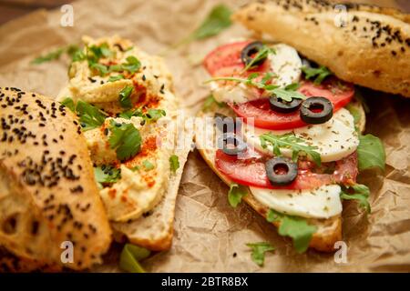 Deux délicieux sandwiches avec houmous, tomate, mozarella, herbes et olives Banque D'Images