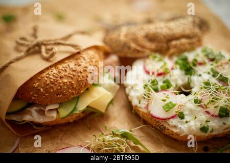 Bagels au jambon, fromage à la crème, houmous, radis emballés dans du papier de cuisson marron prêt à emporter Banque D'Images