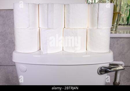 Huit rouleaux de toilettes blancs empilés sur une citerne blanche dans une salle de bains / toilettes / toilettes. Banque D'Images