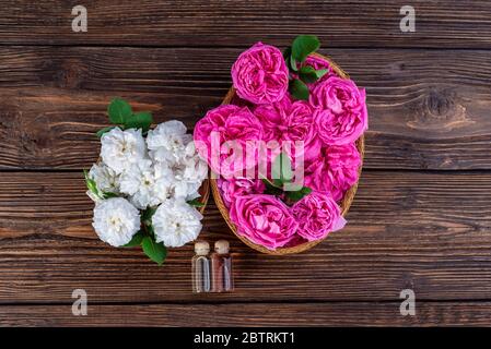 Roses Damas roses roses et blanches dans un panier avec des flacons d'essence de rose Banque D'Images