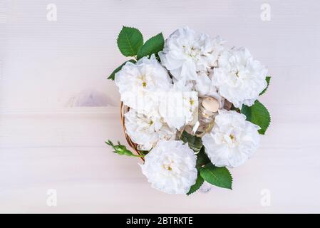 Roses Damas blanches dans un panier avec des flacons d'essence de rose Banque D'Images