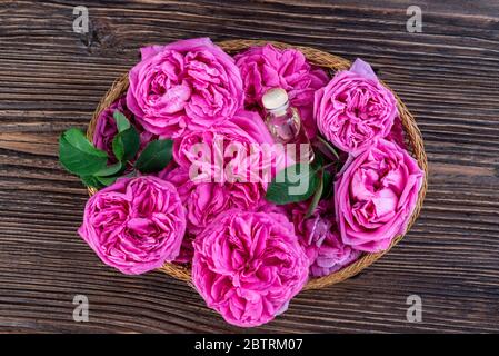 Roses Damas roses roses et blanches dans un panier avec des flacons d'essence de rose Banque D'Images