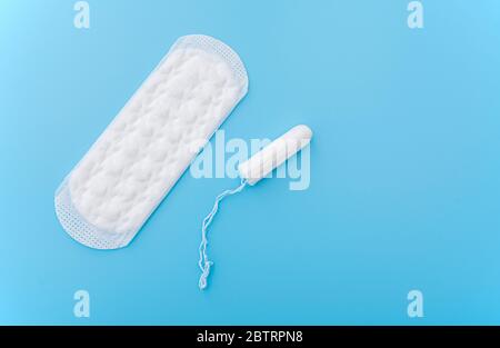 Serviette hygiénique et tampon de menstruation sur fond bleu, image de concept sur le cycle menstruel des femmes, vue du dessus Banque D'Images