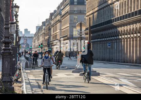 Paris, France - 14 mai 2020 : jeune femme sur son vélo avec un masque chirurgical pour se protéger du covid-19 dans une rue de Paris Banque D'Images