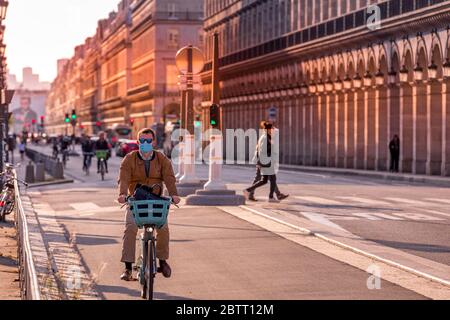 Paris, France - 14 mai 2020 : homme sur son vélo avec un masque chirurgical pour se protéger du covid-19 dans une rue de Paris Banque D'Images