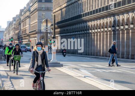 Paris, France - 14 mai 2020 : jeune femme sur son vélo avec un masque chirurgical pour se protéger du covid-19 dans une rue de Paris Banque D'Images