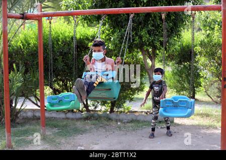 Bagdad. 27 mai 2020. Des enfants iraquiens portant un masque facial jouent sur une balançoire à Bagdad, en Irak, le 27 mai 2020. Le Ministère iraquien de la santé a déclaré mercredi qu'un total de 5,135 cas de COVID-19 avaient été confirmés depuis l'apparition de la maladie dans le pays, dont 175 étaient morts. Crédit: Xinhua/Alay Live News Banque D'Images