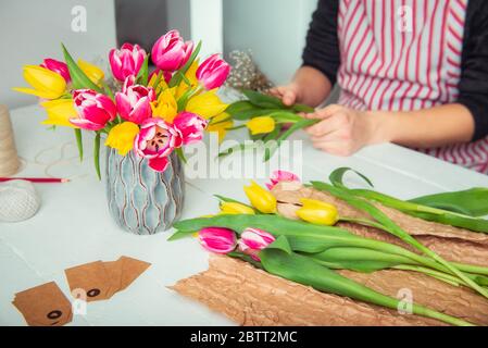 Vase concentré avec fleurs et flou aucun visage jeune homme faisant le bouquet de printemps avec des tulipes. Auto-éducation en ligne de floristry. Apprentissage de l'arrang de fleur Banque D'Images
