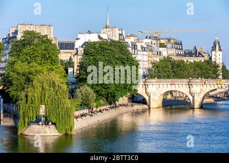 Paris, France - 14 mai 2020 : vue sur les personnes assises et ensoleignant sur les rives de la Seine, sur l'Ile de la Cité, près du Pont neuf et de la place d Banque D'Images