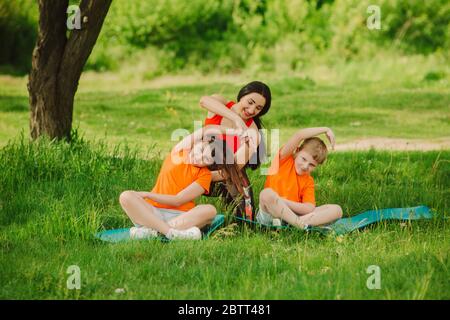 L'entraîneur aide les enfants à terminer l'exercice. Faites du sport en plein air. Concept de mode de vie sain. Mise au point douce Banque D'Images