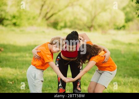 Un coach de fitness aide les enfants à faire l'exercice. Faites du sport en plein air. Concept de mode de vie sain. Yoga pour bébé, entraînement physique. Banque D'Images