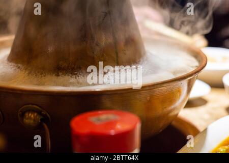 Une casserole chinoise traditionnelle de style Beijing chauffée au charbon avec un pot en laiton en forme de beignet. Placé au centre de la table à manger, ingrédients crus et frais fr Banque D'Images
