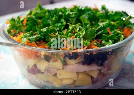 Préparation des pommes de terre dans des pots pour la cuisson. Pommes de terre sautées, viande, oignons, carottes, persil, champignons dans une casserole en verre. Cuisine rurale Banque D'Images