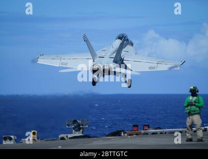 Un avion de chasse F/A-18F Super Hornet de la marine américaine, affecté aux Chevaliers noirs de VFA 154, sort du pont de vol du porte-avions de la classe Nimitz USS Theodore Roosevelt le 26 mai 2020 en mer des Philippines. L'équipage COVID-NEGATIVE est revenu de la quarantaine et le navire a poursuivi son déploiement prévu dans l'Indo-Pacifique. Banque D'Images