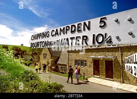 Cotswolds 1970's Road Sign pour CHIPPING CAMPDEN & BOURTON SUR L'EAU vintage rétro voie vieux panneau de route vacances famille staycation Royaume-Uni Angleterre archive voyage vacances vacances, avec de vieux panneaux de direction en bois pour Chipping Campden et Bourton sur l'eau. Destinations de vacances dans les Cotswolds, avec des familles de visiteurs se promenant sur la traditionnelle voie historique des Cotswolds au Royaume-Uni Banque D'Images