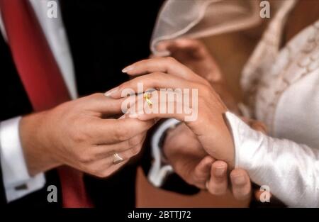 BAGUE DOIGTS MARIAGE MARIAGE MAINS PLACEMENT BAGUE OR CLASSIQUE BLANC MARIAGE EN GROS PLAN mariée et marié échangeant des anneaux de mariage d'or à cérémonie de mariage romantique et formelle blanche Banque D'Images