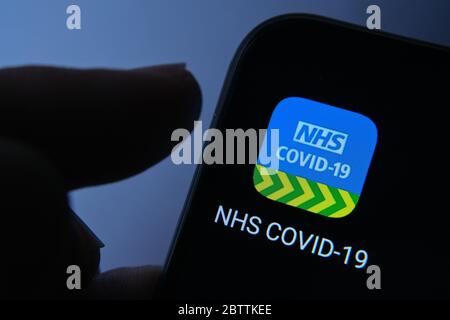 NHS COVID-19 sur le téléphone mobile et le doigt le lançant. Banque D'Images