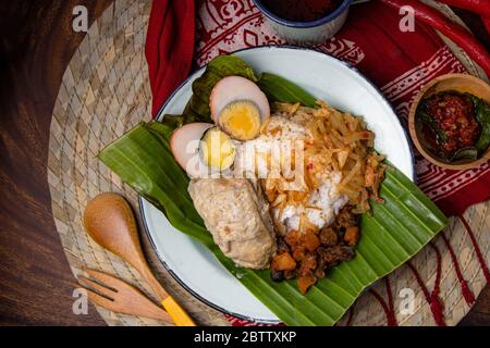 Asie cuisine asiatique traditionnelle nasi liwet cuit dans le lait de coco, bouillon de poulet épices enveloppées dans la feuille de banane de Solo Central Java Javanais Banque D'Images