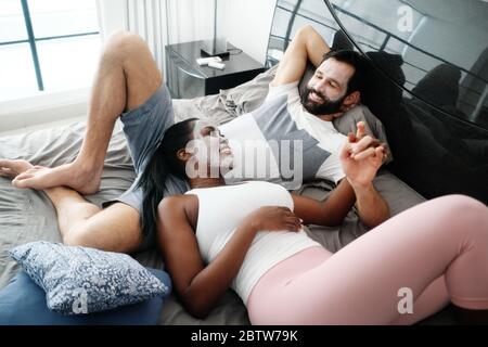 Homme et femme heureux avec masque de beauté sur le lit Banque D'Images