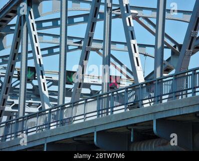 Ponts de fer de l'autre côté de la rivière et feux de signalisation, flèches rouges vertes sur le sol, ciel bleu frais Banque D'Images