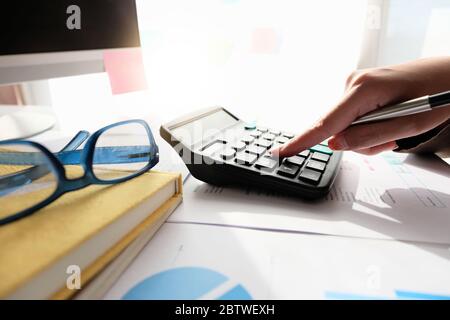 Gros plan comptable utilisant la calculatrice pour calculer les dépenses financières au bureau à domicile Banque D'Images