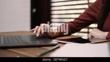 Gros plan des mains de femme utilisant sur ordinateur portable pour l'apprentissage en ligne sur table en bois à la maison Banque D'Images