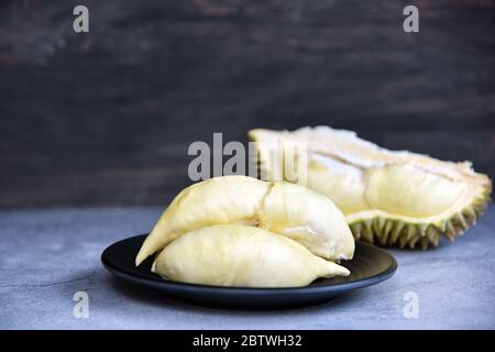 rippé durien. Roi des fruits. Le durian est un fruit tropical populaire en Thaïlande. Bétel de durian sur plat noir avec pelage durian sur fond de couleur sombre. Banque D'Images