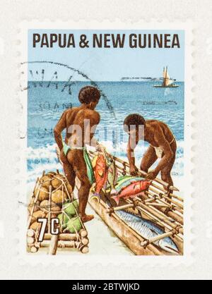 SEATTLE WASHINGTON - 25 mai 2020 : timbre de Papouasie et de Nouvelle-Guinée représentant des hommes sur la plage, faisant du commerce de poissons, noix de coco et taro. Scott # 332 Banque D'Images