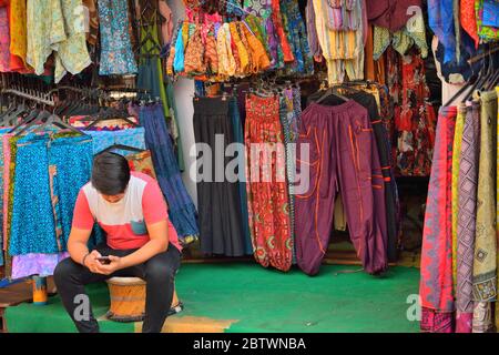 Un homme vendant des vêtements colorés dans sa boutique. Banque D'Images