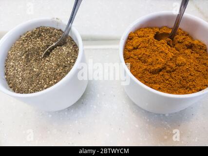 Poivre noir moulu et poivre de Cayenne dans la tasse en porcelaine avec la cuillère en métal pour l'assaisonnement au restaurant thaïlandais. Banque D'Images