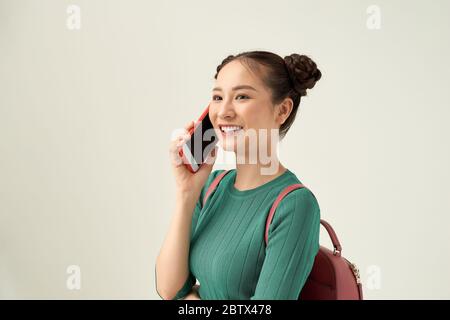 Image d'une belle fille heureuse posant isolée sur fond blanc parlant par téléphone mobile. Banque D'Images