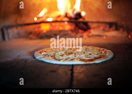 La pizza rustique est retirée de la cuisinière chaude où elle a été cuite. Faire cuire à l'aide d'une pelle spéciale pour les retirer. Ce restaurant dispose d'un four à bois spécial Banque D'Images