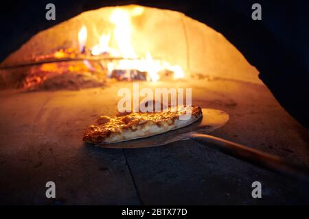 La pizza rustique est retirée de la cuisinière chaude où elle a été cuite. Faire cuire à l'aide d'une pelle spéciale pour les retirer. Ce restaurant dispose d'un four à bois spécial Banque D'Images