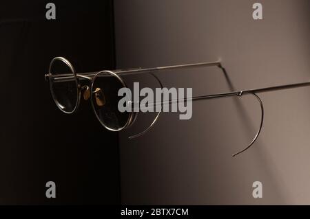 Lunettes de Henry W Dennis avec étui à lunettes. Les verres ont des lentilles rondes, circulaires et fines barres de branches en métal faites du même matériau que le cadre des lentilles. De petits coussinets de nez brunis sont fixés au pont. Les lunettes reposent sur un petit tissu rose usé à l'intérieur d'un étui doublé de velours. Banque D'Images