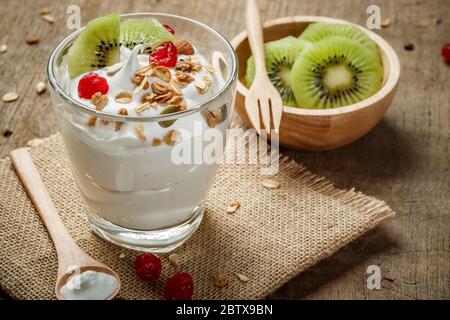 Du yaourt ou de la crème fraîche dans un verre avec kiwi - sur la table en bois Banque D'Images