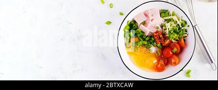 Ingrédients des omelettes : œufs, jambon, tomates, herbes vertes, lait et fromage sur la table lumineuse. Vue de dessus, au-dessus, bannière Banque D'Images