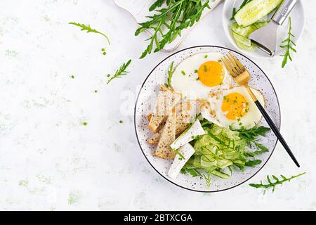 Petit-déjeuner anglais - œufs frits, fromage feta, concombre et arugula. Cuisine américaine. Vue de dessus, au-dessus, espace de copie Banque D'Images