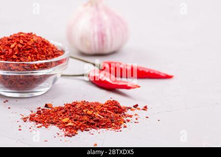 Assaisonnement à la Harissa dans une assiette de verre, ail frais et deux piments Banque D'Images