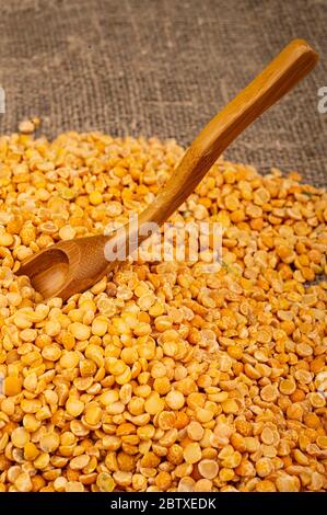 Petits pois jaunes dispersés sur un fond de toile de fond à texture grossière. Céréales traditionnelles pour faire des soupes et du porridge. Gros plan Banque D'Images